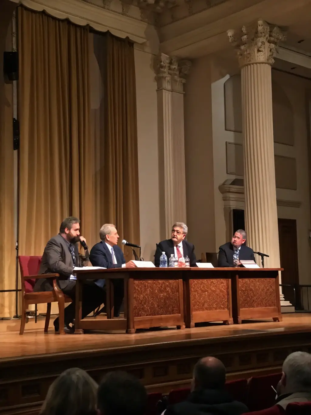 A photograph of a panel discussion in progress at a leadership conference in Delhi, India. Four panelists are seated at a table, and a moderator is asking a question.